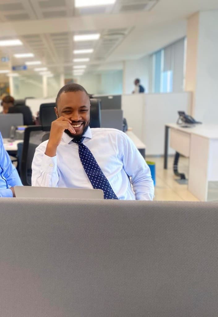 Jindu Kwentua, data scientist and engineer, in business attire at an office desk.